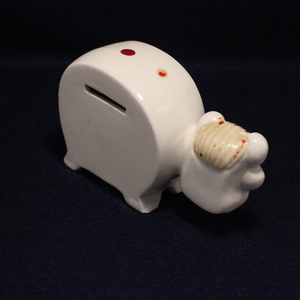 White ceramic piggy bank shaped like a foot with a shell on a dark background