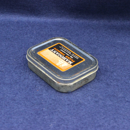 Close‑up of tobacco tin lid with detailed typography and authentic vintage wear.