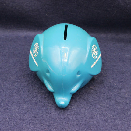 Turquoise piggy bank shaped like a dolphin on a dark blue background