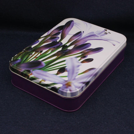 Square tin box with floral design on a dark background