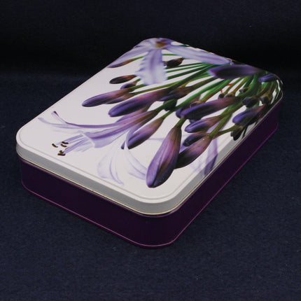 Rectangular tin box with purple flower design on a dark background