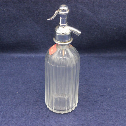 Clear glass misting bottle with silver top on a blue background