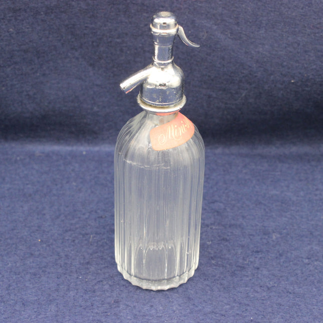 Clear glass nisting bottle with silver top on a blue background