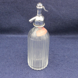 Clear glass nisting bottle with silver top on a blue background
