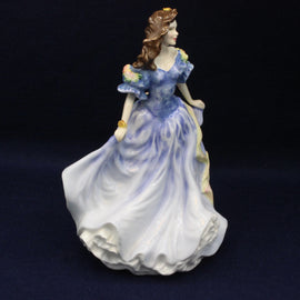 Porcelain figurine of a woman in a blue dress on a dark background