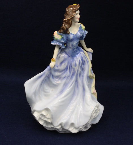 Porcelain figurine of a woman in a blue dress on a dark background