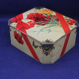 Decorative hexagonal tin with floral and ribbon design on a blue background