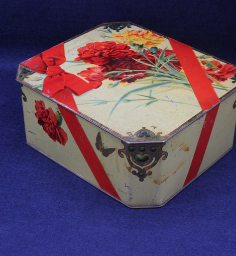 Decorative hexagonal tin with floral and ribbon design on a blue background