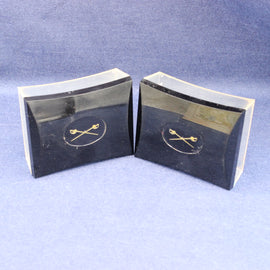 Two black rectangular objects with gold emblem on a blue background