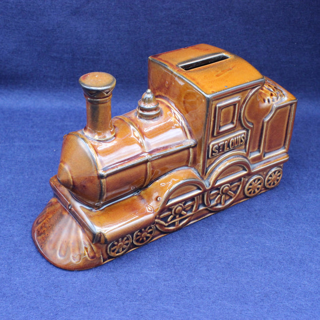Ceramic train-shaped piggy bank on a blue background