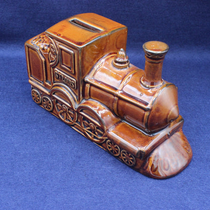 Brown ceramic train-shaped money box on a blue background