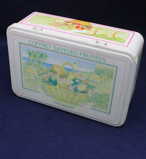Decorative tin box with fruit-themed design on a dark background