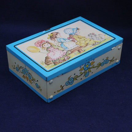 Decorative tin box with colorful illustration on a dark blue background