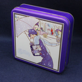Tin box with a decorative design of a woman holding an umbrella on a snowy street.