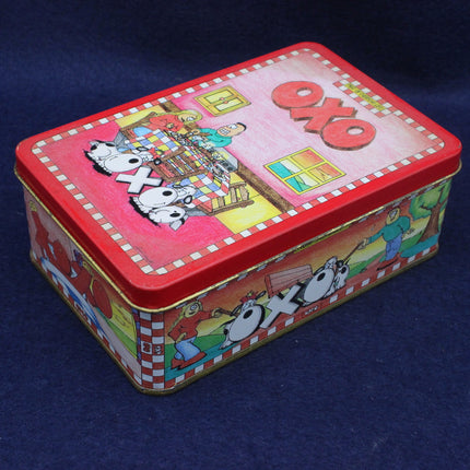 Colorful tin box with cartoon characters and 'Oxo' branding on a dark blue background
