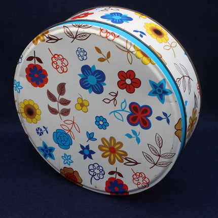 Round tin with colorful floral design on a dark background.