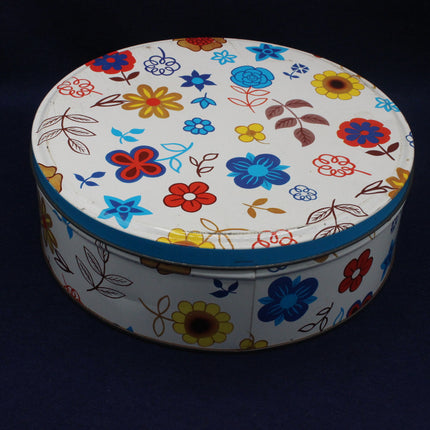 Round biscuit tin with floral pattern on a dark background