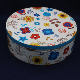 Round biscuit tin with floral pattern on a dark background