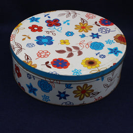 Round decorative biscuit tin with colorful floral patterns on a dark background
