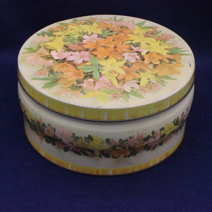 Round floral tin box with a colorful lid on a dark blue background
