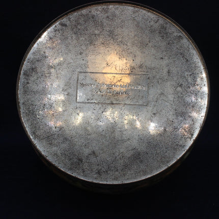 Round metallic object with engraved text on a black background