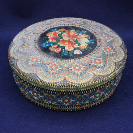 Ornate round biscuit tin on a blue background