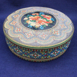 Decorative round tin with floral design on a blue background