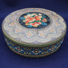 Decorative round tin with floral design on a blue background