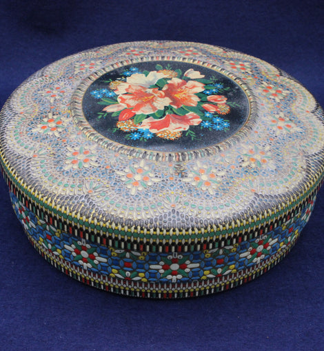 Decorative round tin with floral design on a blue background