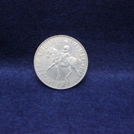 Silver Queen Elizabeth 1977 coin with the queen on a horse on a blue fabric background