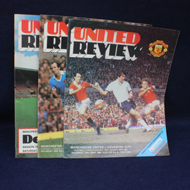 Three Manchester United review magazines on a dark background