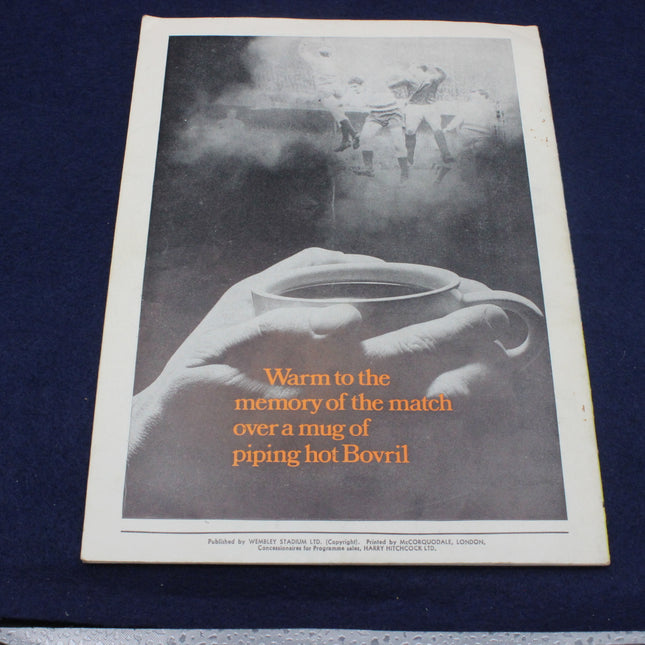 Vintage advertisement for Bovril showing a hand holding a mug with steam, on a dark background.