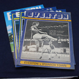 Stack of Everton football club programmes on a dark background