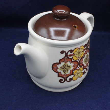 Ceramic teapot with floral design on a blue background