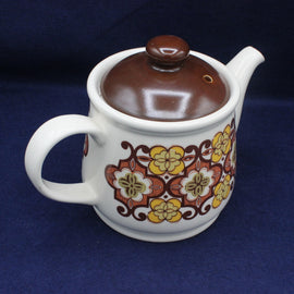 Decorative ceramic teapot with floral patterns on a blue background