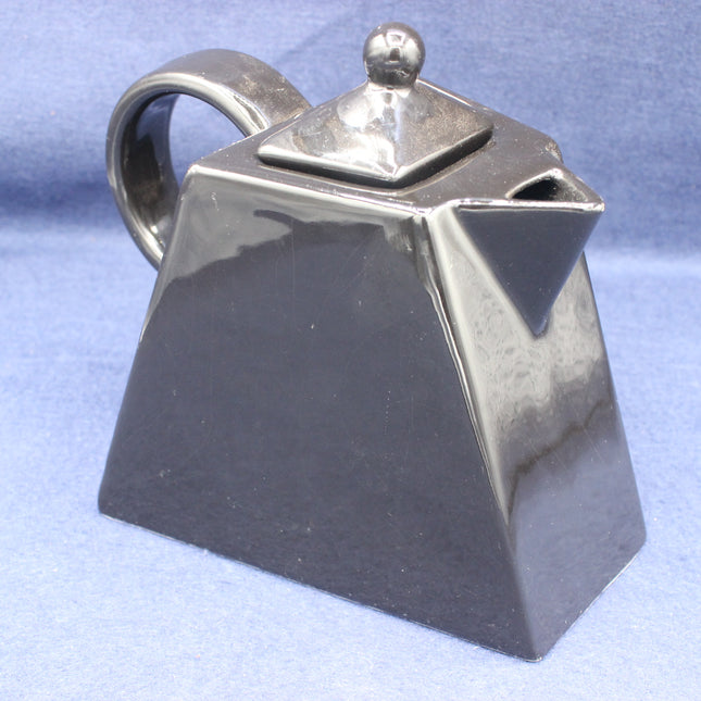 Black square shaped teapot on a light blue background