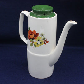 White ceramic teapot with floral design and green lid on a blue background
