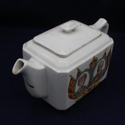 White ceramic teapot with decorative portraits on a black background