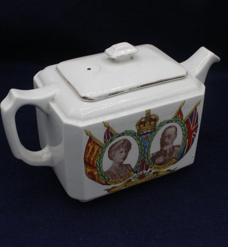 White teapot with royal portraits and flags on a dark background