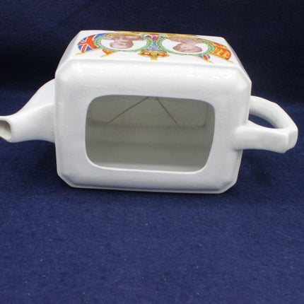 White ceramic teapot with colorful lid design on a blue background