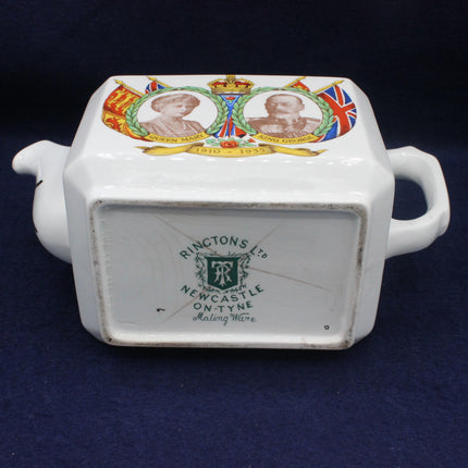 White ceramic container with decorative top featuring portraits and a Union Jack, on a dark blue background.