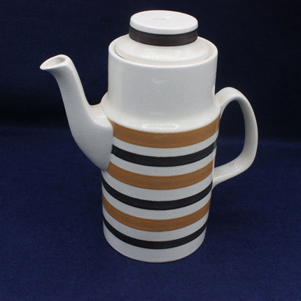 White teapot with striped brown and black design on a dark blue background