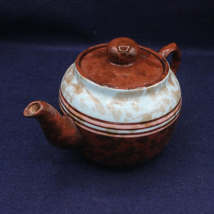 Ceramic teapot with brown and white design on a dark blue background