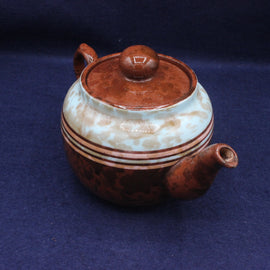 Ceramic teapot with brown and beige design on a dark blue background
