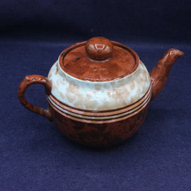 Ceramic teapot with brown and white design on a blue background