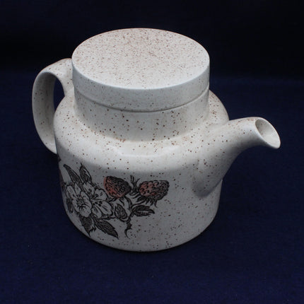 Speckled ceramic teapot with floral design on a dark background