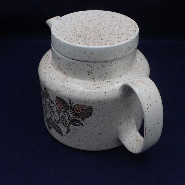 Speckled ceramic teapot with floral design on a dark background