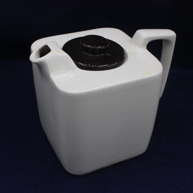 White plastic container with a black lid on a dark background