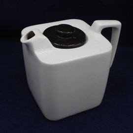 White plastic container with a black lid on a dark background