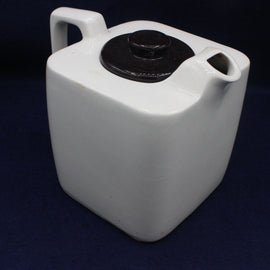 White ceramic teapot with black lid on a dark blue background